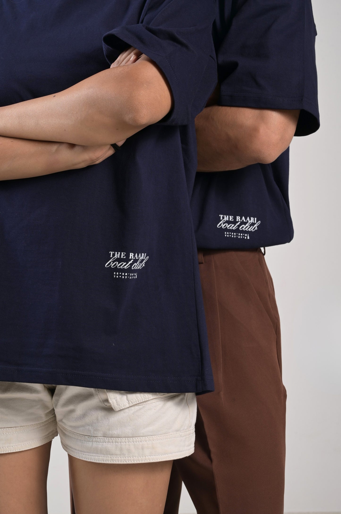 Two people wearing navy blue shirts with a boat club print in the bottom corner