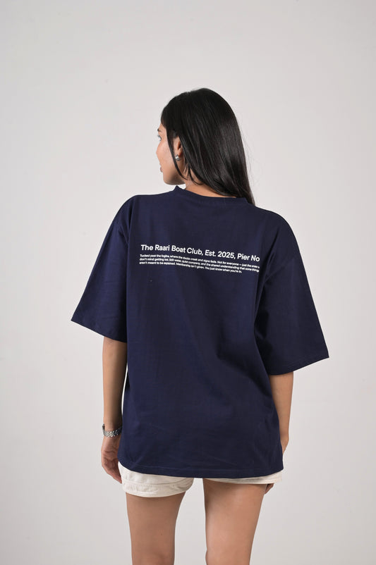 Person wearing a navy blue t-shirt with text on the back against a plain background